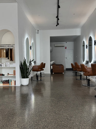 Modern salon interior with brown chairs, mirrors, and shelves. Hustle and Co Richmond - Hair Extension and Colour Specialists